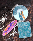 Various colourful JAYD Swimwear keychains sitting on a rock