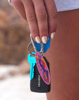 Hand holding a keychain with colourful JAYD Swimwear 'dive in with confidence' keychain attached.