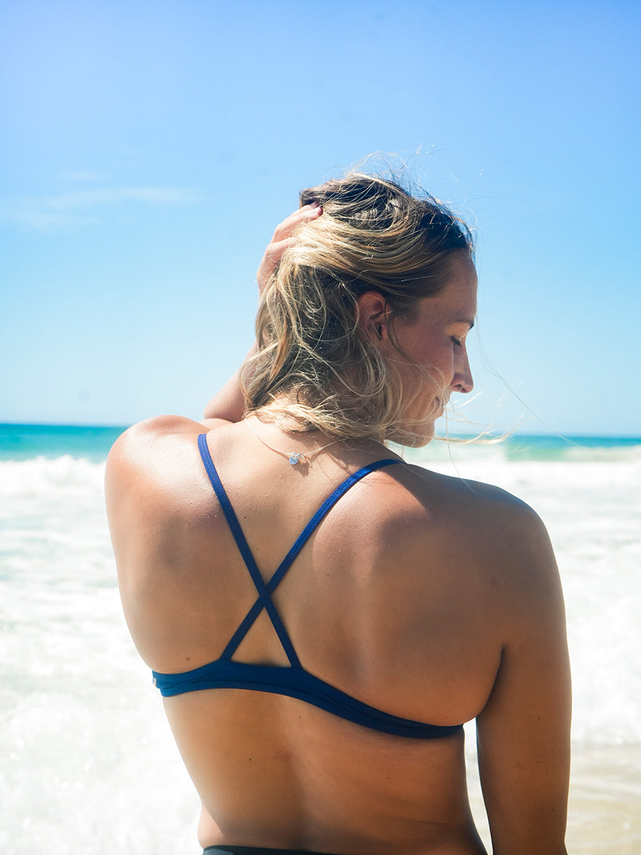 Model wearing the JAYD Swimwear Kiama Top in navy, showcasing the timeless fixed-back triangle designed for even tension distribution.