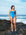 Open water swimmer Madi Armstrong standing on a rock at the beach wearing the JAYD Swimwear Cancun blue one piece swimsuit with contrasting cobalt shoulder straps.