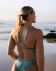 Fixed-back JAYD Swimwear Lennox one piece swimsuit in matcha green with contrasting blue shoulder straps and hip cut-out panels.