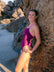 JAYD Swimwear athlete Charlotte Derbyshire leaning against a rock wearing the Lennox one piece swimsuit in sangria with contrasting orchid shoulder straps and 5 hip panel cut-outs.