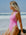 JAYD model Izzy wearing the seamless front Levanto one piece in fairy floss pink, sitting on a rock gazing out at the ocean.