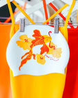 JAYD Swim cap featuring koi fish illustration with yellow flowers and swimsuits in the background.