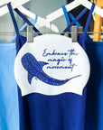 White swim cap with illustration of a whate shark and inspirational text 'embrace the magic of movement'.