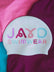 White swim cap with colorful squiggly  text 'JAYD SWIMWEAR' on a multicolored background