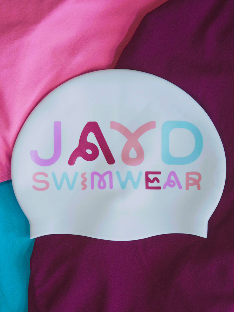White swim cap with colorful squiggly  text 'JAYD SWIMWEAR' on a multicolored background