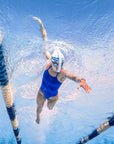 A swimmer underwater in a blue one-piece swimsuit, using the glacier Blue FINIS Stability Snorkel.
