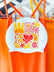White JAYD Swim cap with colourful collage style illustrations hanging on a rack with swimsuits in the background