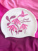 A white swim cap featuring a pink and magenta floral design with a hummingbird and the text 'Jayd Swimwear', displayed on a draped magenta fabric background.