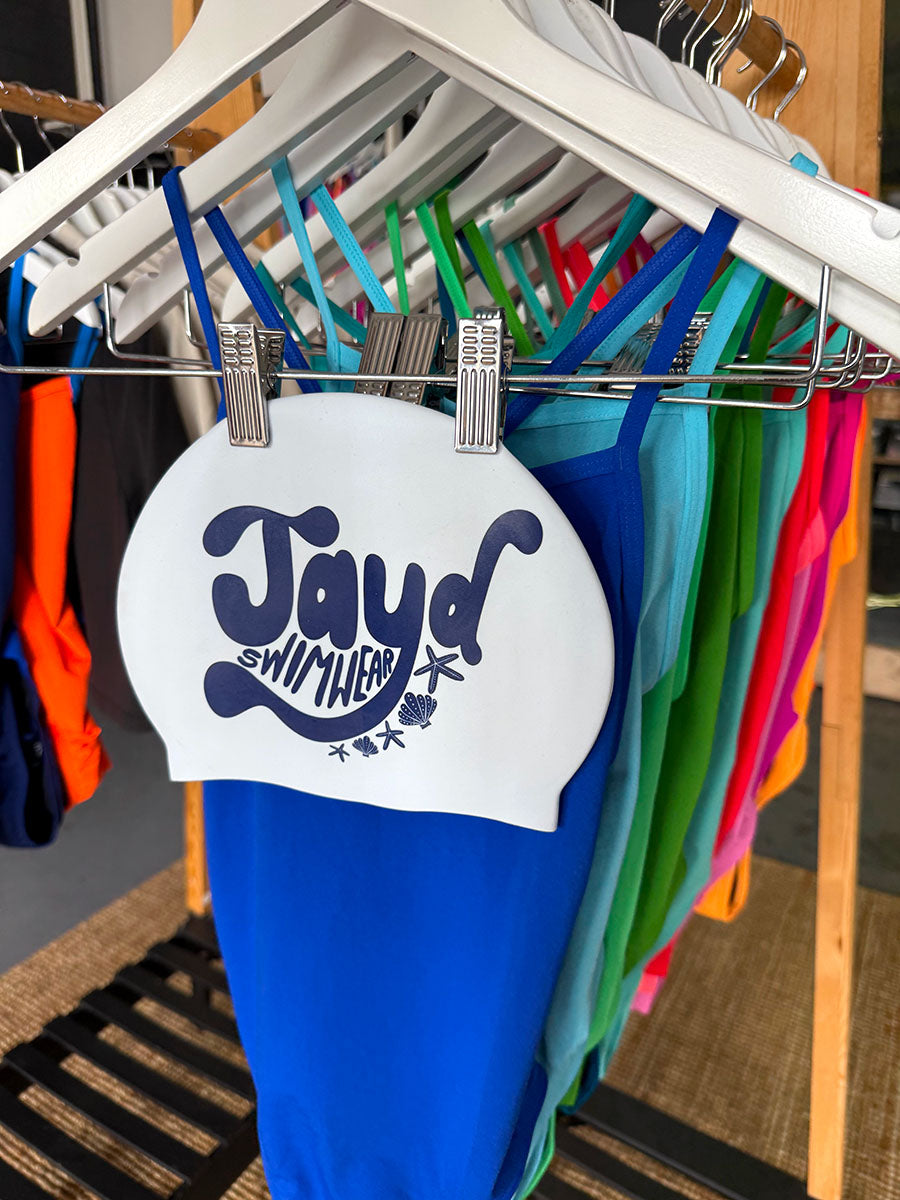 JAYD Swim Cap featuring moody dark blue hues accompanied by shells and star fish against a matching blue swimsuit.