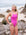 JAYD Swimwear model standing on a rocky beach with the ocean in the background, wearing the Tallow one piece swimsuit in orchid pink..