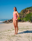JAYD model Kiera standing on a beach wearing the Tallow one piece swimsuit in vibe.