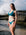 JAYD Swimwear model Milly wearing the Cove Vienna bikini top stands on a rocky beach with ocean waves crashing in the background.