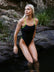 Athlete Keira Stephens sitting on the edge of a rock in the JAYD Swimwear Zambia Black x Spice one piece.