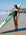 Surf athlete Molly Shivnan standing on a beach in the JAYD Swimwear Long Torso Zimmy One-Piece swimsuit, holding her green ski board and looking out towards the ocean.