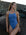 Surf life saving athlete Claudia Slaven standing in front of dark beach rocks wearing the Zimmy one piece in Storm blue.