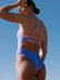 Woman wearing Airlie fixed back one piece in Lilac Haze with contrasting straps and back detailing. 