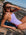 Woman in a lilac haze athletic one piece sitting on a rock by the beach