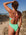 Woman in a meadow green and fairy floss pink fixed back one piece standing on a beach with ocean view
